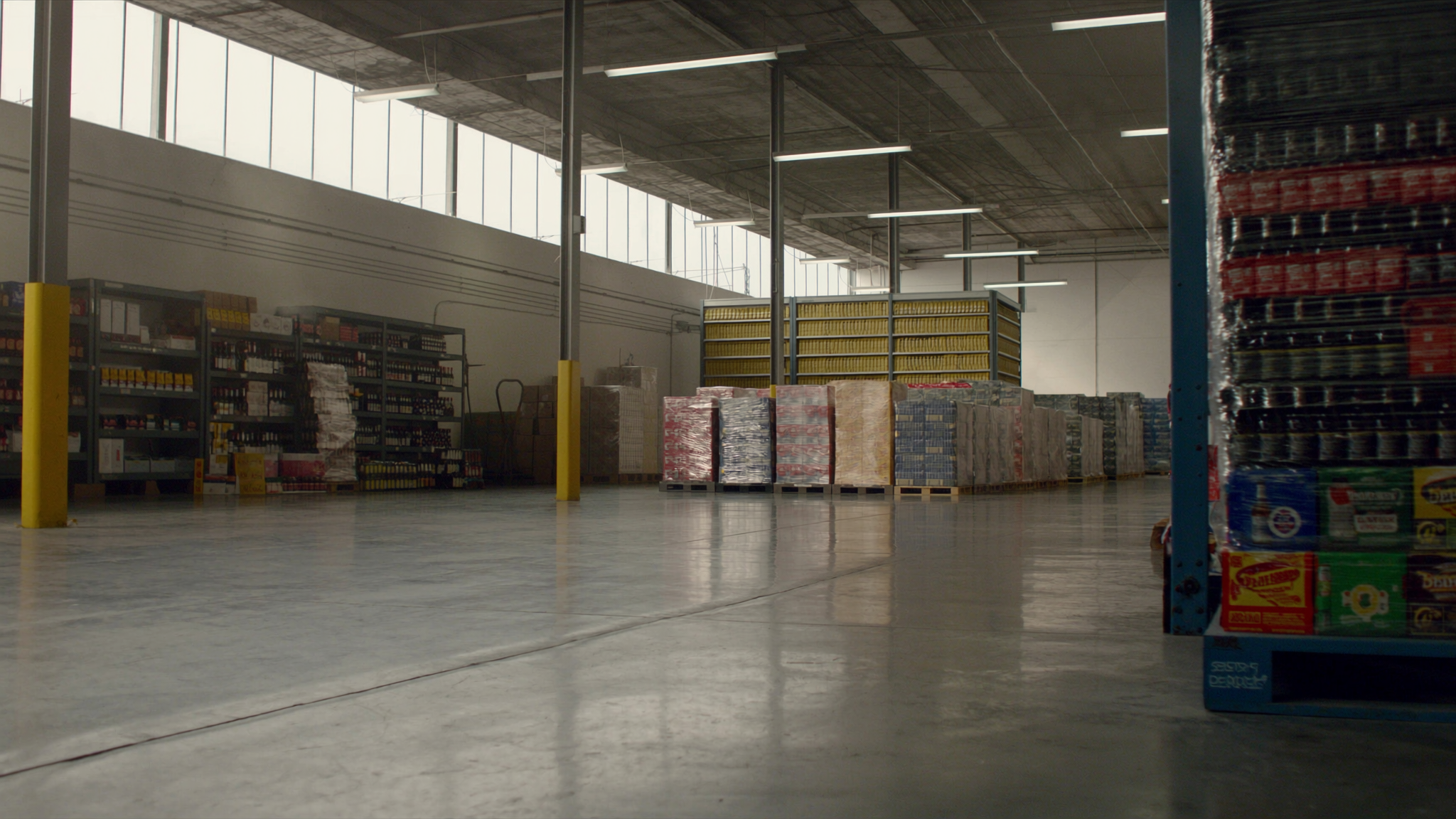 Traditional American beverage wholesale warehouse — pallets of beer cases and tall liquor racks, the operational core of an alcoholic beverage wholesaler
